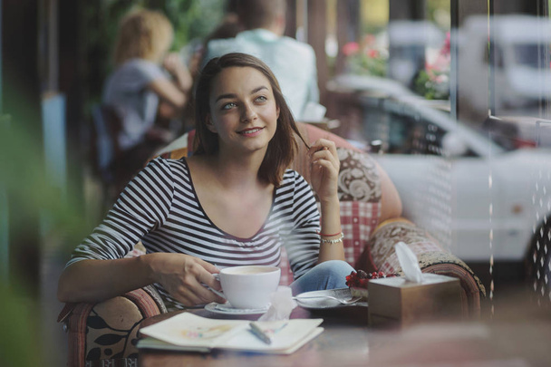 νεαρή γυναίκα που κάθεται εσωτερικούς χώρους στα αστικά café - Φωτογραφία, εικόνα