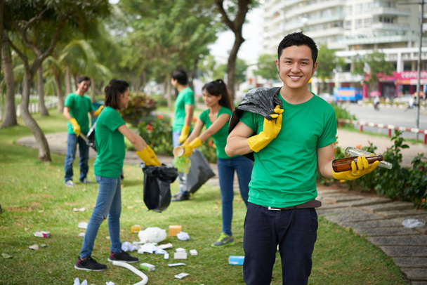Voluntario vietnamita sosteniendo botellas de vidrio
 - Foto, Imagen