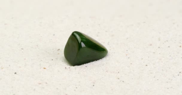 Камень из нефрита вращается на белом песке
 - Кадры, видео