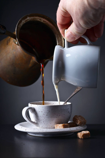 Xícara de café com leite e açúcar mascavo no fundo escuro
 - Foto, Imagem