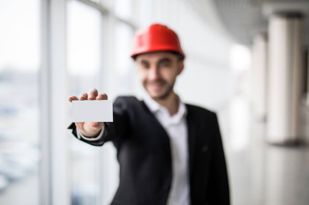 Trabajador de la construcción con tarjeta de visita en blanco en la construcción del edificio
. - Foto, imagen
