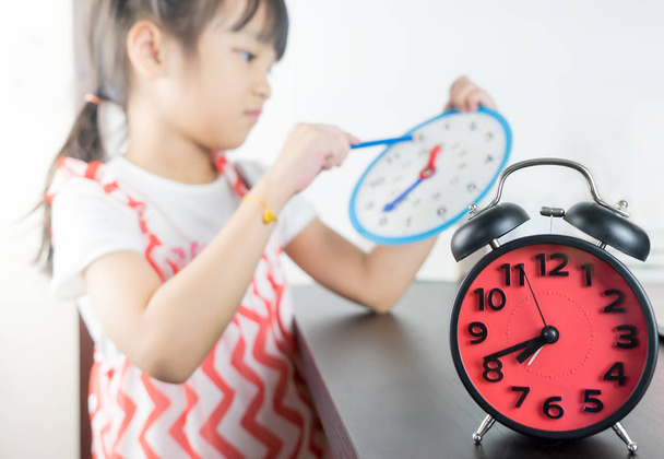 Petite fille asiatique tenant horloge jouet temps scolaire
 - Photo, image