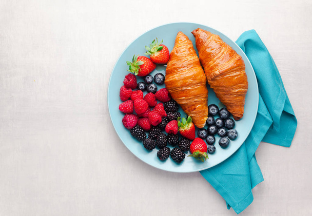 Summer breakfast on a blue plate. Fresh ripe berries and pastrie - Фото, зображення