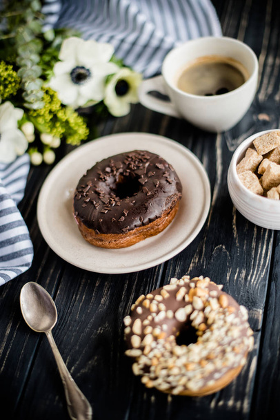 Cup of coffe and a chocolate donuts on black wood - 写真・画像