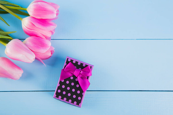 Букет рожевих тюльпанів з подарунковою коробкою на синьому дерев'яному фоні
 - Фото, зображення