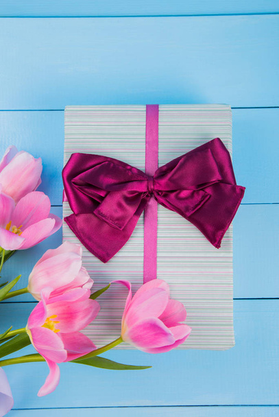 Bouquet di teneri tulipani rosa con confezione regalo su dorso in legno blu
 - Foto, immagini