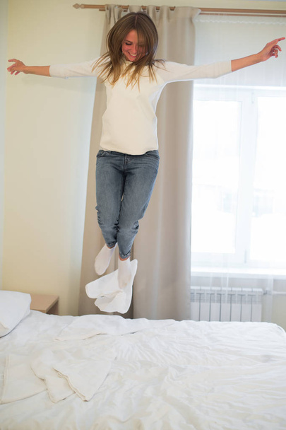 Portrait of a young happy woman jumping on the bed - Valokuva, kuva