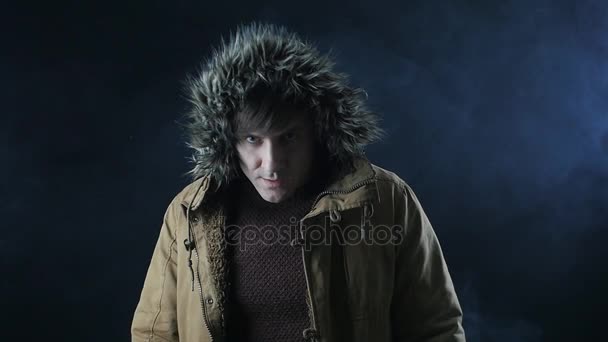 νεαρός άνδρας σε μια κουκούλα που αναζητά σε ένα σκοτεινό δωμάτιο μυστηριώδη γεμάτη με καπνό - Πλάνα, βίντεο