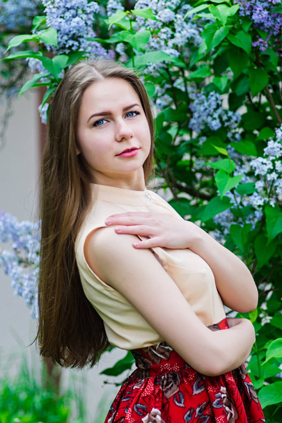 Pretty girl with posing at garden against blooming lilac. - Foto, Bild