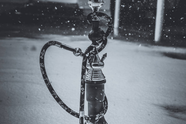 Iso vesipiippu metallista, lasista ja keramiikasta valmistetulle tupakalle. Sataa lunta. Lumen tausta. Valkoinen
 - Valokuva, kuva