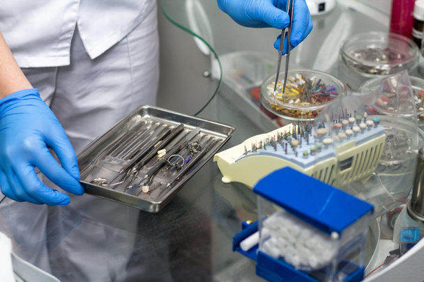 стоматолог тримає стоматологічні інструменти та матеріали
 - Фото, зображення