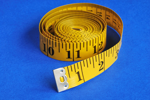 A coiled-like measuring tape isolated on blue background - Photo, Image