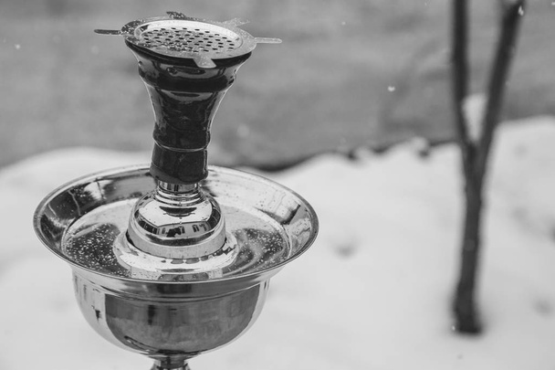 Big hookah for tobacco made of metal, glass and ceramics. Snowing. Snow background. White - Photo, Image
