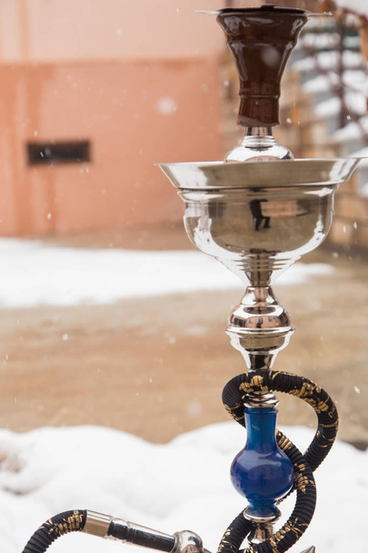 Big hookah for tobacco made of metal, glass and ceramics. Snowing. Snow background. White - Photo, Image