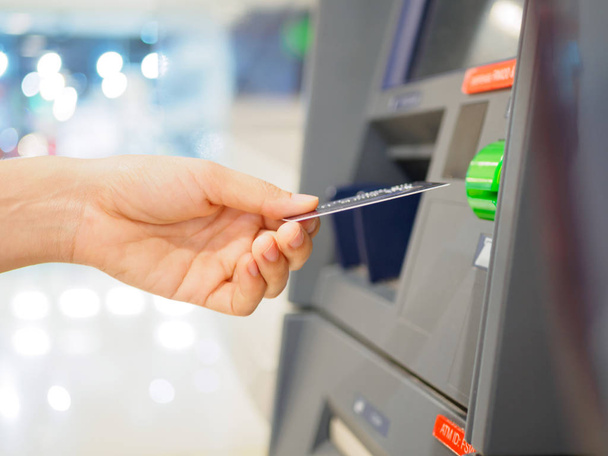 Close-up van vrouw hand debetkaart invoegen in een ATM-machine. horizontale schot. - Foto, afbeelding