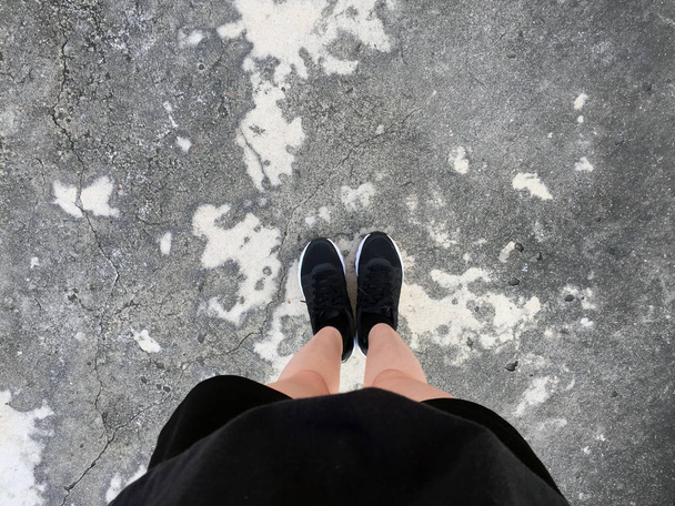Pieds féminins en Sneakers noires sur fond de sol
 - Photo, image