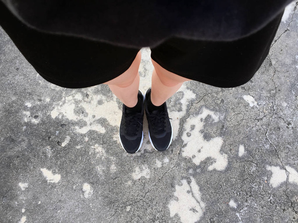 Női lábak Black Sneakers a padlón háttér - Fotó, kép