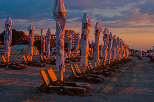 sombrillas en la playa junto al mar. durante el amanecer
 - Foto, Imagen
