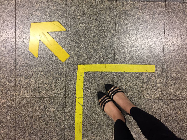 Frauenfüße in schwarzen Schuhen und Pfeil vorwärts  - Foto, Bild