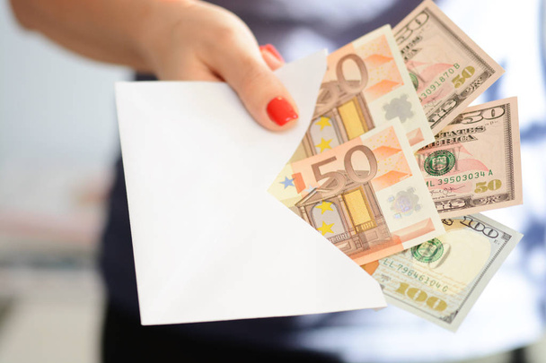 Γυναίκα χέρι κρατά ένα φάκελο γεμάτο χρήματα, δωροδοκώντας έννοια - Φωτογραφία, εικόνα