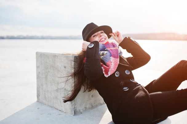 Funny příležitostná mladá dívka v černém kabátě, šátek a klobouk proti fro - Fotografie, Obrázek