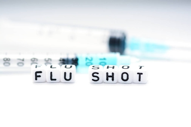 Flu shot text spelled with tiled plastic letters standing next to a syringe  - Фото, зображення