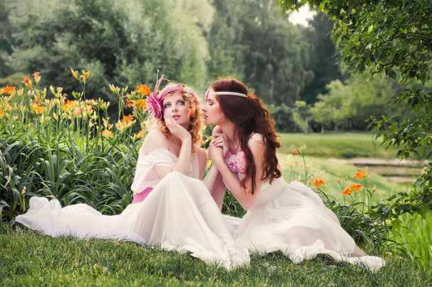 Lovely bridesmaids sitting on the grass. - Фото, изображение