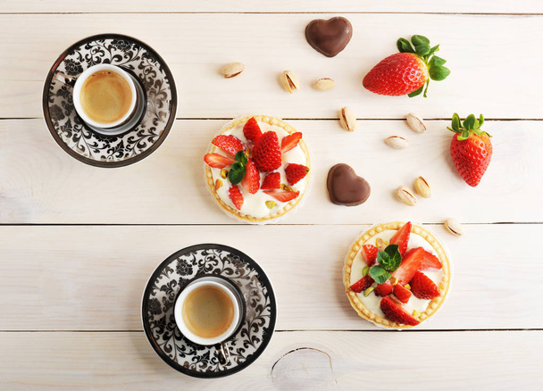 two cups of coffee and a pastry basket with strawberry, pistachi - Photo, image