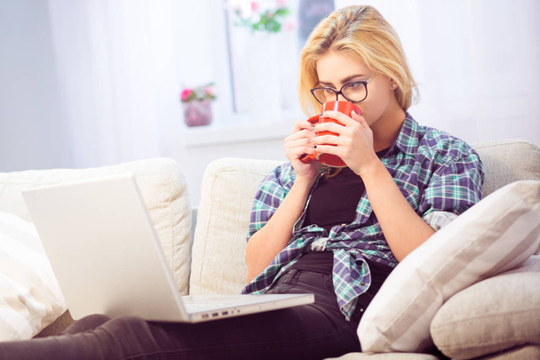 Lady drinking coffee in front of laptop - Photo, Image