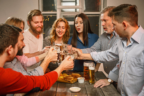 Group of friends enjoying evening drinks with beer - Foto, afbeelding