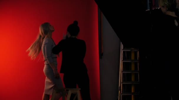 Παρασκήνια: φωτογράφιση στο studio με κορίτσι μοντέλο - παίζει μακριά ξανθά μαλλιά - Πλάνα, βίντεο