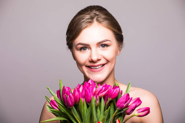 Beautiful girl with flowers tulips in hands on a light background - Фото, изображение