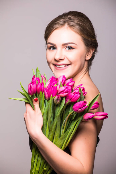 Beautiful girl with flowers tulips in hands on a light background - Фото, зображення