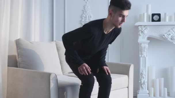 Young Caucasian man sits on sofa and having fun using white VR headset glasses - Video, Çekim