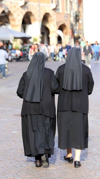 duas irmãs com vestidos pretos e um véu para cobrir a caminhada do cabelo
 - Foto, Imagem