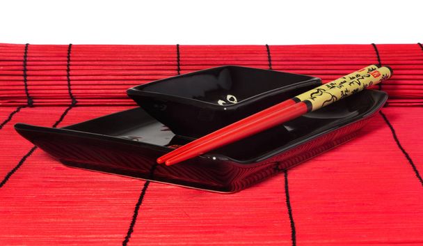 Jogo vermelho e preto de pratos de sushi na esteira de madeira vermelha
. - Foto, Imagem