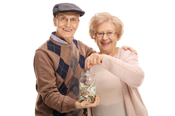 man holding money jar with woman putting coin - Фото, зображення