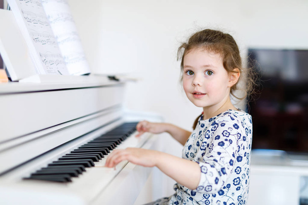 Красива маленька дівчинка грає на піаніно у вітальні або музичній школі
 - Фото, зображення