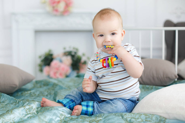 Baby playing with a rattle,sitting on the bed - Fotoğraf, Görsel