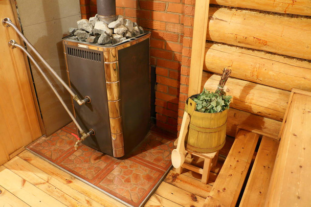 Het interieur van het Russische bad. Sauna kachel en het vat met een bezem in de sauna ruimte. - Foto, afbeelding