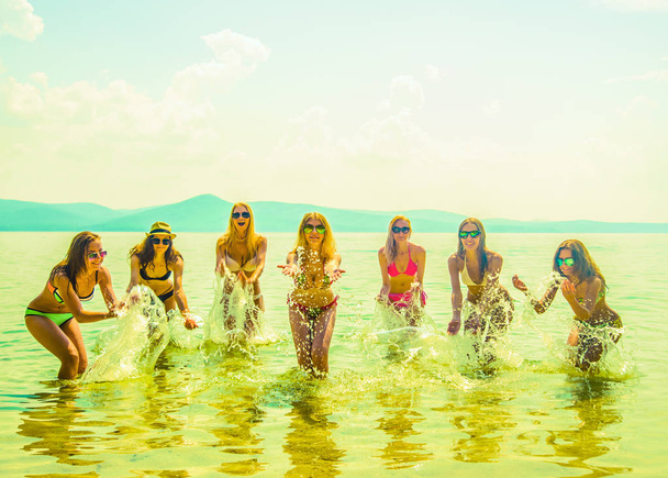 mladá skupina žen skákání v oceánu při západu slunce. Tým dospělých dívek, skákání do vody  - Fotografie, Obrázek