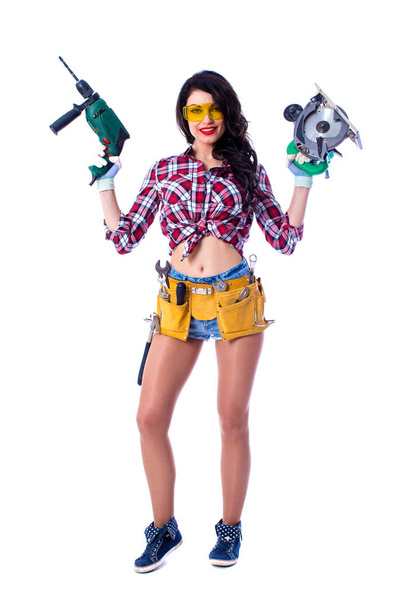 Sexy brunette woman mechanic with circular saw and perforator - Foto, Imagen