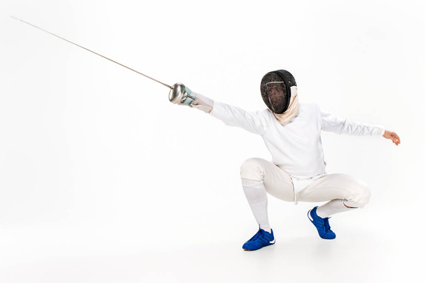 Man wearing fencing suit practicing with sword against gray - Фото, зображення