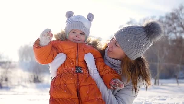Dziewczyna gra z dzieckiem w słoneczny w okresie zimowym. Trzyma na rękach - Materiał filmowy, wideo