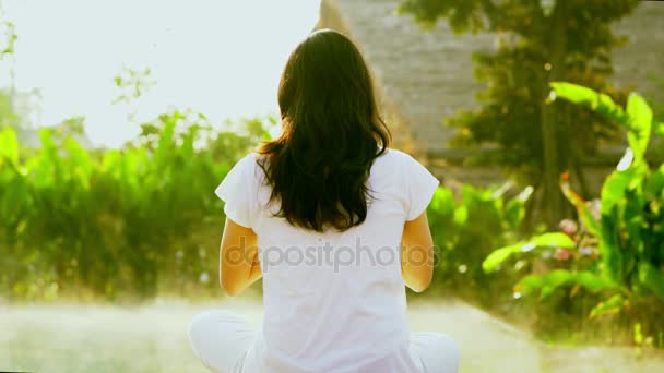 asiatische Mädchen üben Yoga neben Wellness-Spa-Pool in der Sonne mit grünem Hintergrund und Morgennebel Zeitlupe Schuss - Filmmaterial, Video
