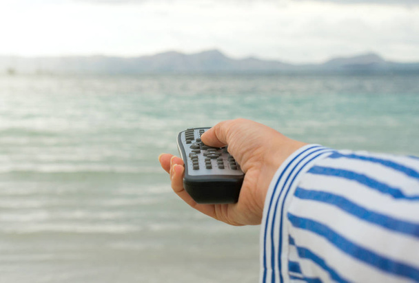 Magic remote control. Image that you can choose anything you want, for example your vacations near the sea. - Photo, Image