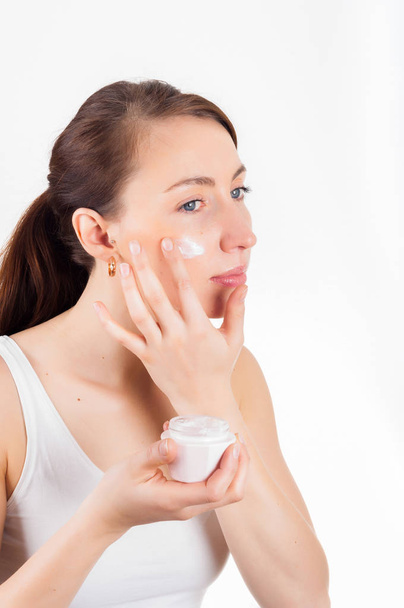 Beauty concept. Skin care. Beautiful Woman putting face cream on - Photo, Image