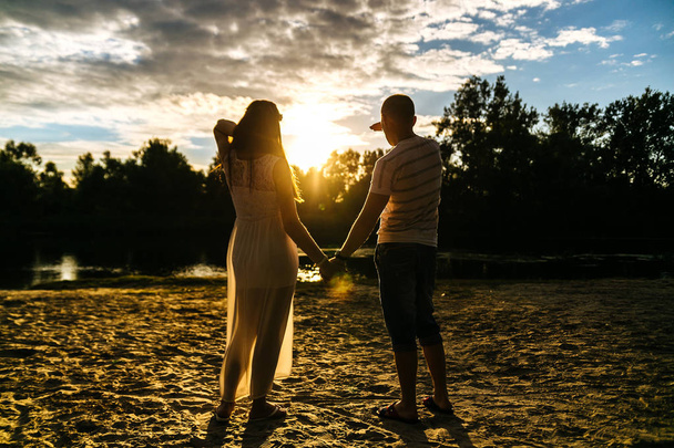 Силуэт счастливой молодой влюбленной пары, смотрящей на закатное небо b
 - Фото, изображение