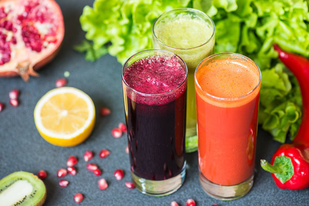 three glasses of different fresh juice. Beet, carrot and kiwi juices on grey background - Photo, Image