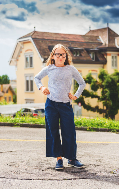 Ao ar livre engraçado retrato de um bonito pouco 9-10 anos de idade menina vestindo top azul, denim culottes e óculos
  - Foto, Imagem